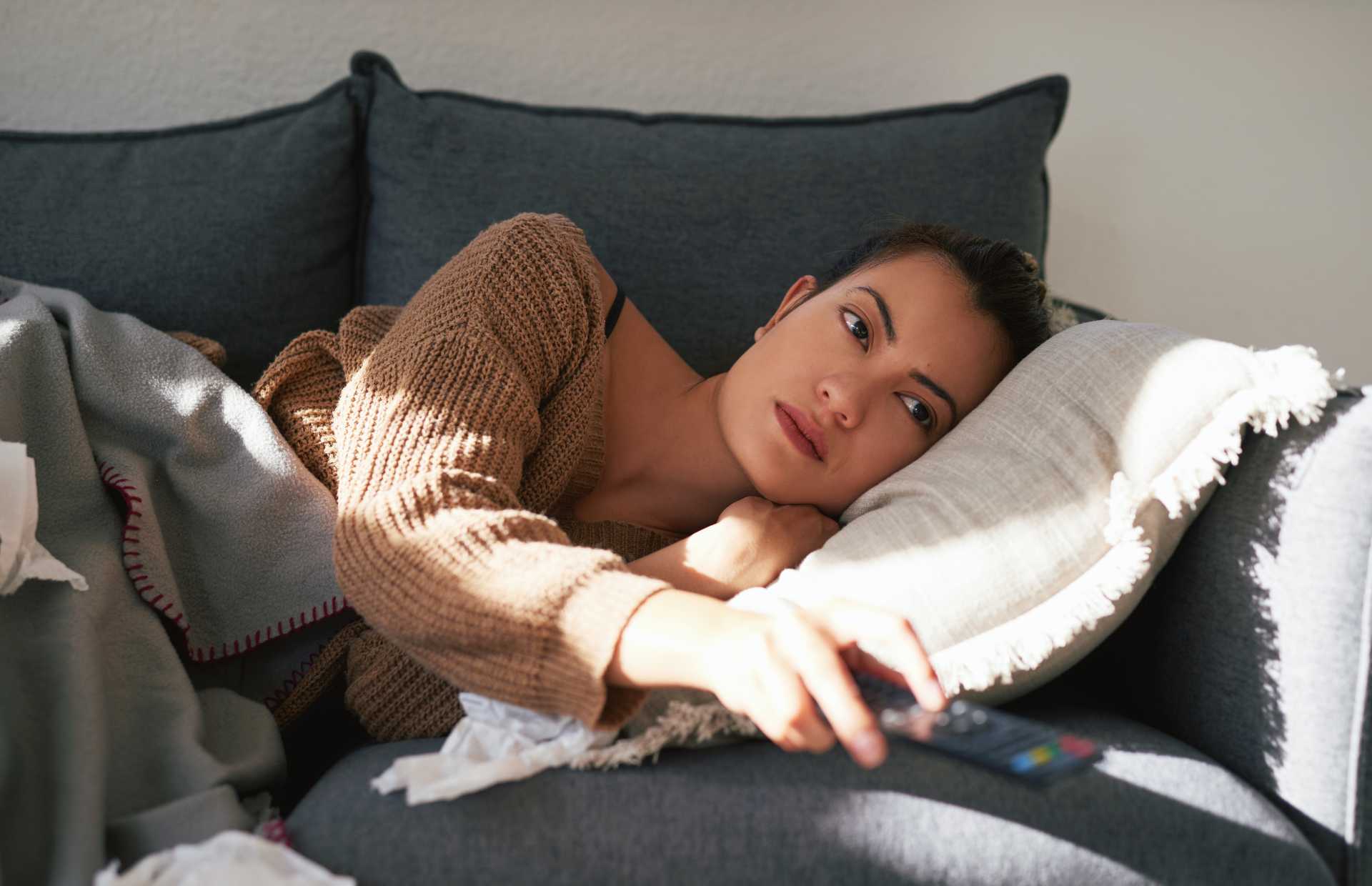 Sad woman lying on couch after binge