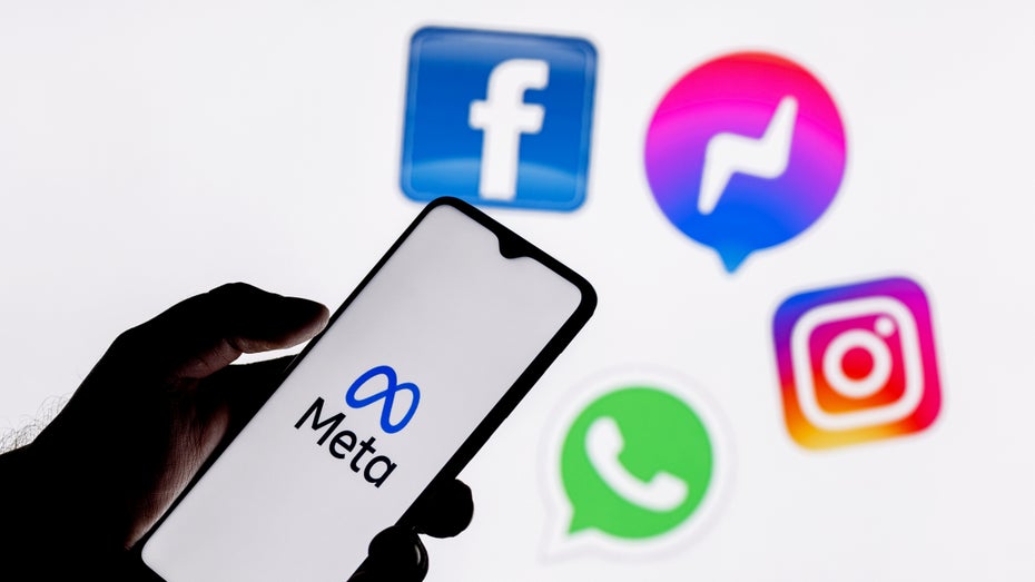 Eine Person hlt ein Smartphone in der Hand mit Social-Media-Icons im Hintergrund